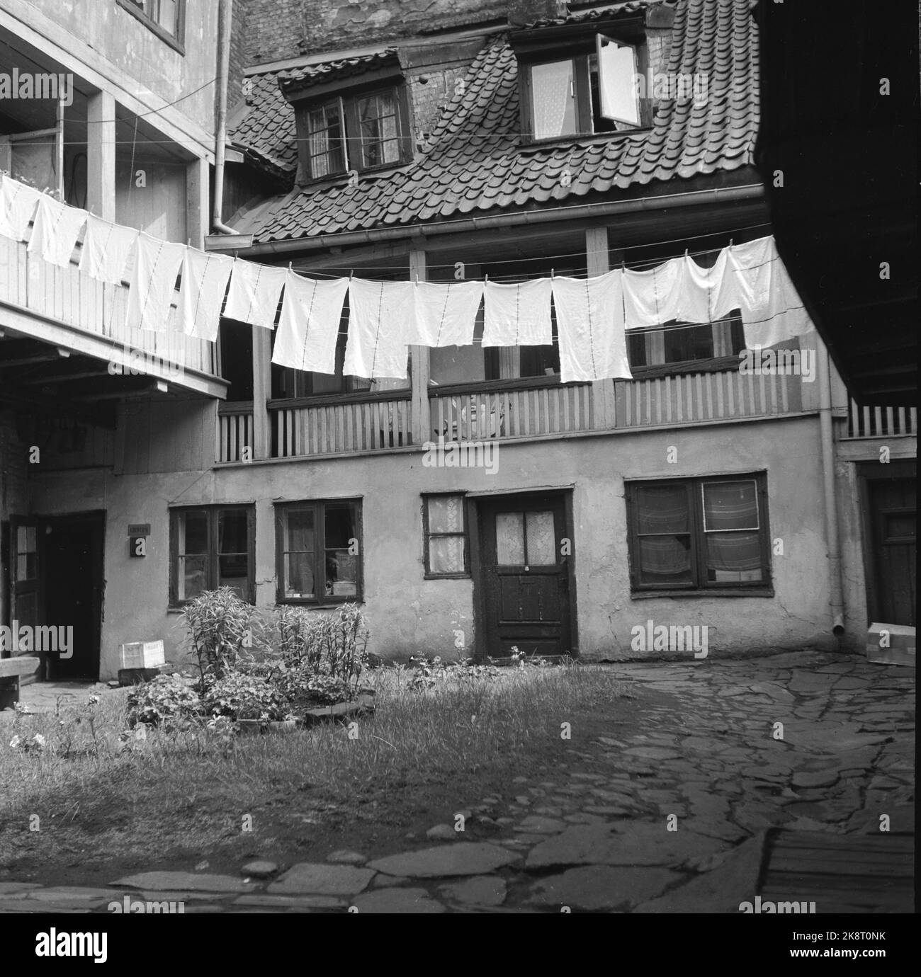 Oslo 19510609 Oslo. Alte Farm in Tomtegata. Hier hängt die Wäsche zum Trocknen. Ansonsten zeichnet sie sich durch eher in verschiedenen Größen und wildwachsende Pflanzen aus. Die Häuser sind vom Verfall geprägt. Foto: Stage / NTB / NTB Stockfoto