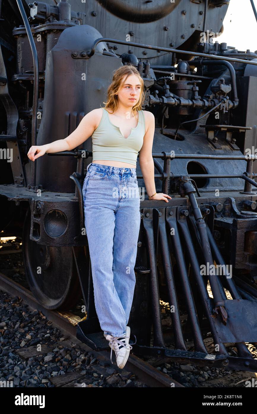 Teenage Girl in Trainyard stehend vor der alten schwarzen Dampfmaschine Stockfoto
