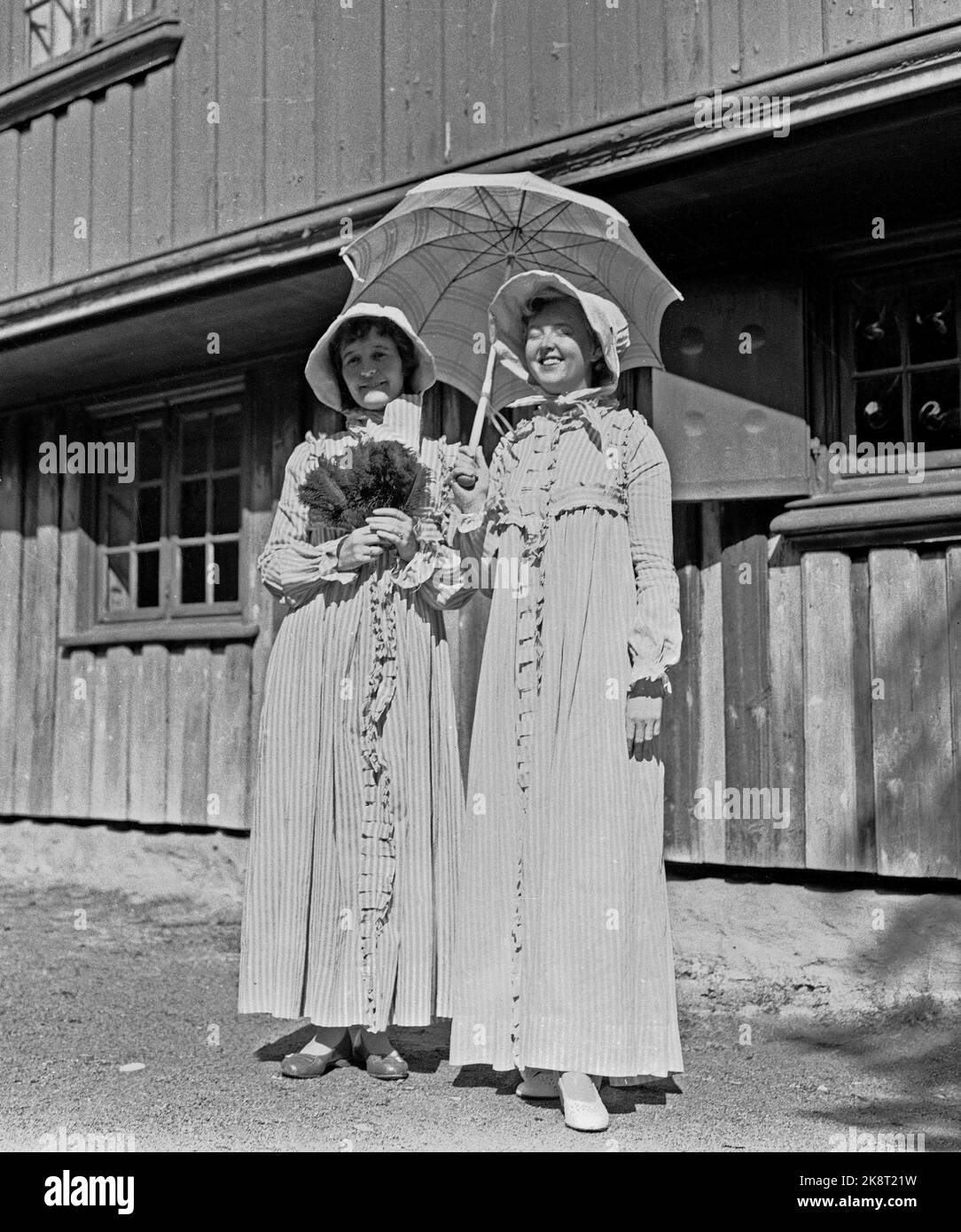 Bygdøy 19570825 Parade von alten Fahrrädern im Volksmuseum. Unter den Zuschauern zwei Frauen, modisch gekleidet mit langen Kleidern und Küssen, und Sonnenschirm. Foto: Jan Nordby / NTB / NTB Stockfoto