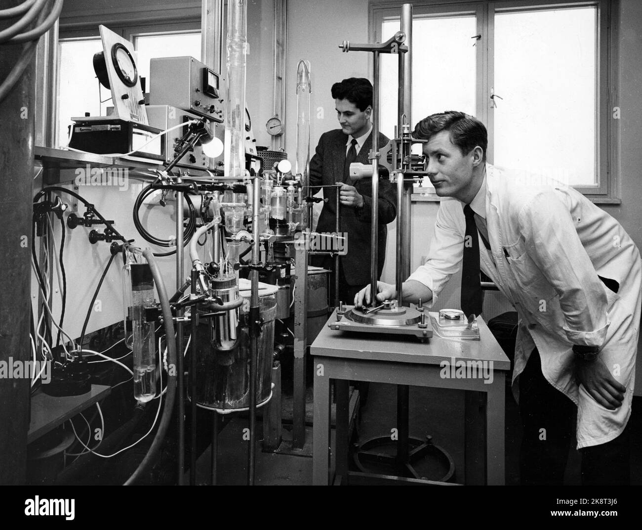 Oslo 195702020. In den Laboratorien im Blindern Research Center wird eine solide Basis für den Fortschritt der norwegischen Industrie gelegt. Die zunehmende Automatisierung in der Branche erfordert, dass die Menschen jederzeit auf dem neuesten Stand sind. Dr. Phil. Per Kofstad und der Chemiker Nils Oluf Andresen sind dabei, die Oxidationsbeständigkeit von Titanlegierungen in verschiedenen Temperaturbereichen zu untersuchen. Foto: Aage Storløkken / Aktuell / NTB Stockfoto