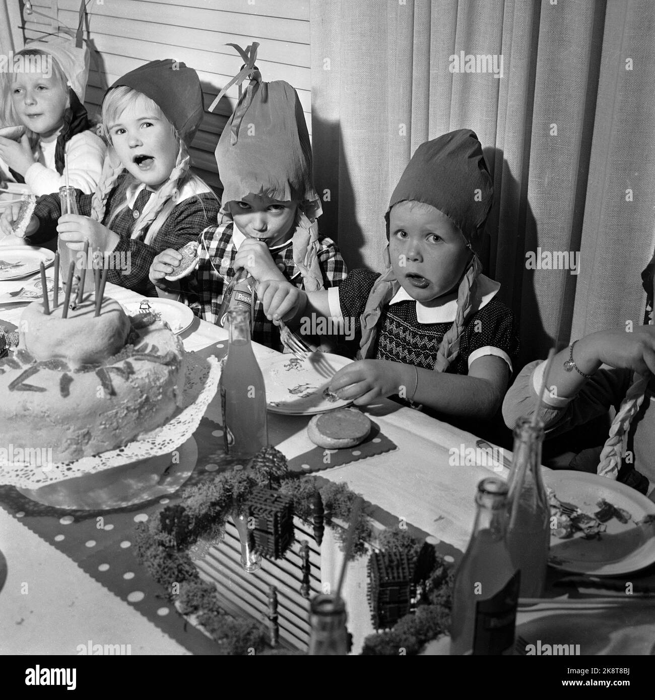 Oslo 19631127 Birthday Company / Children's Company / Birthday Company mit der Ole Moes Road Familie auf Nordstrand. Fröhliche Kinder am Kuchentisch, mit hausgemachten Papierhüten auf den Köpfen. Geburtstagskuchen und alkoholfreie Getränke. Foto: Erik Thorberg / NTB / NTB Stockfoto