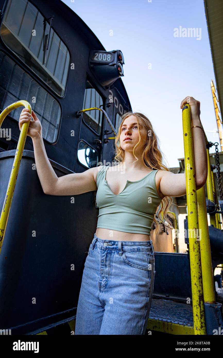 Junge Frau, die auf der Treppe eines Diesel-Elektrozugmotors steht Stockfoto
