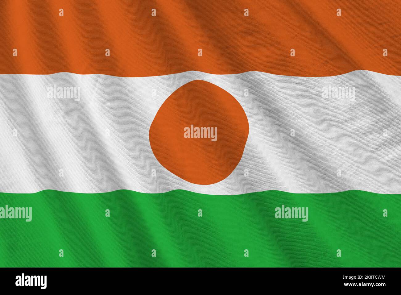 Niger-Flagge mit großen Falten, die aus nächster Nähe unter dem Studiolicht im Innenbereich winken. Die offiziellen Symbole und Farben in Stoff Banner Stockfoto