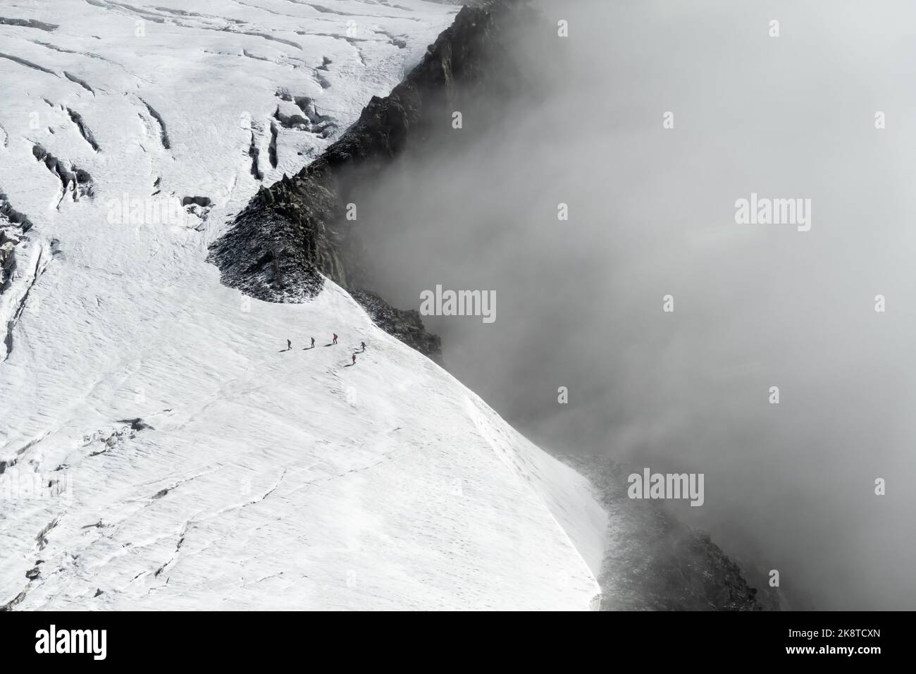 Chamonix, Frankreich - 31. August 2022: 5 Wanderer auf dem Glacier du Geant im Mont-Blanc-Massiv, die sich von der Klippe entfernen, während sich Wolken bewegen Stockfoto