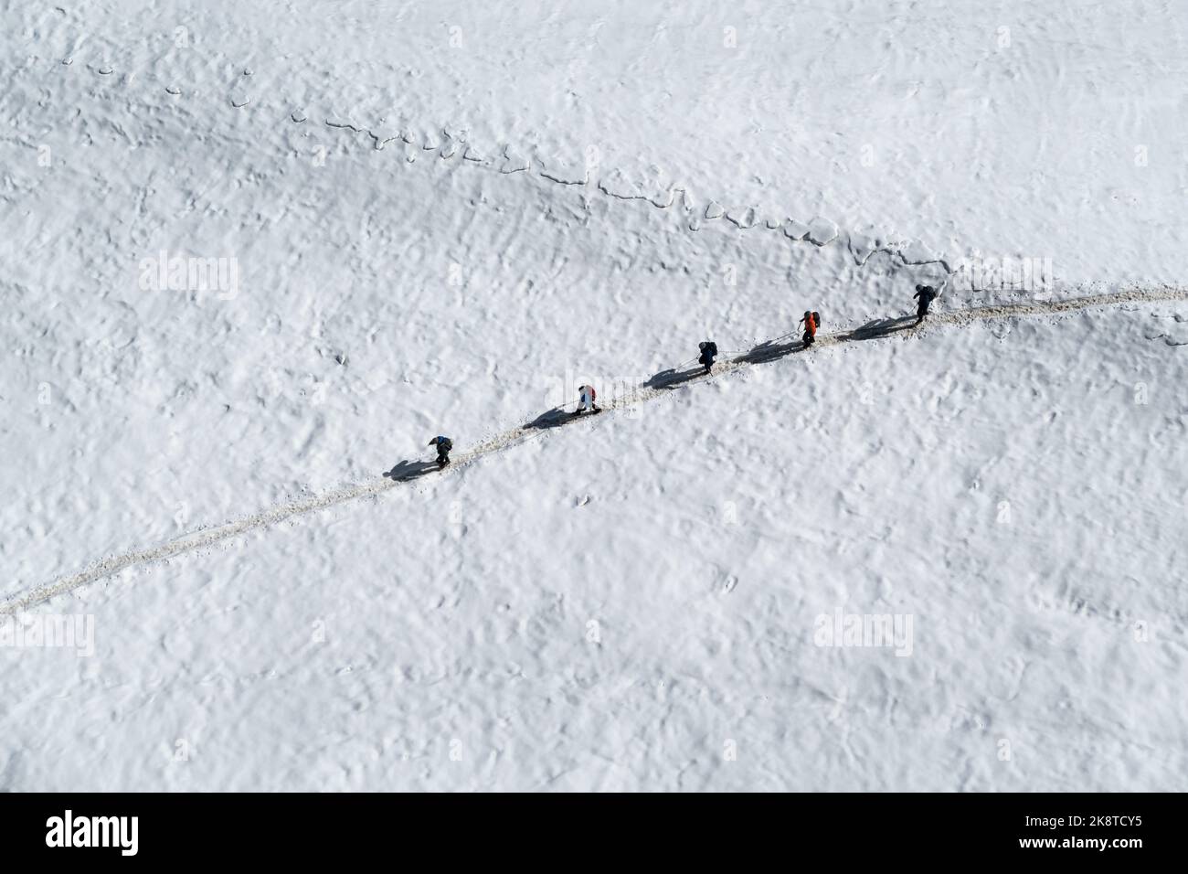 Chamonix, Frankreich - 31. August 2022: Blick von oben auf 5 Wanderer, die im Sommer zusammen mit Seilen über den Gletscher des Valle Blanche wandern Stockfoto