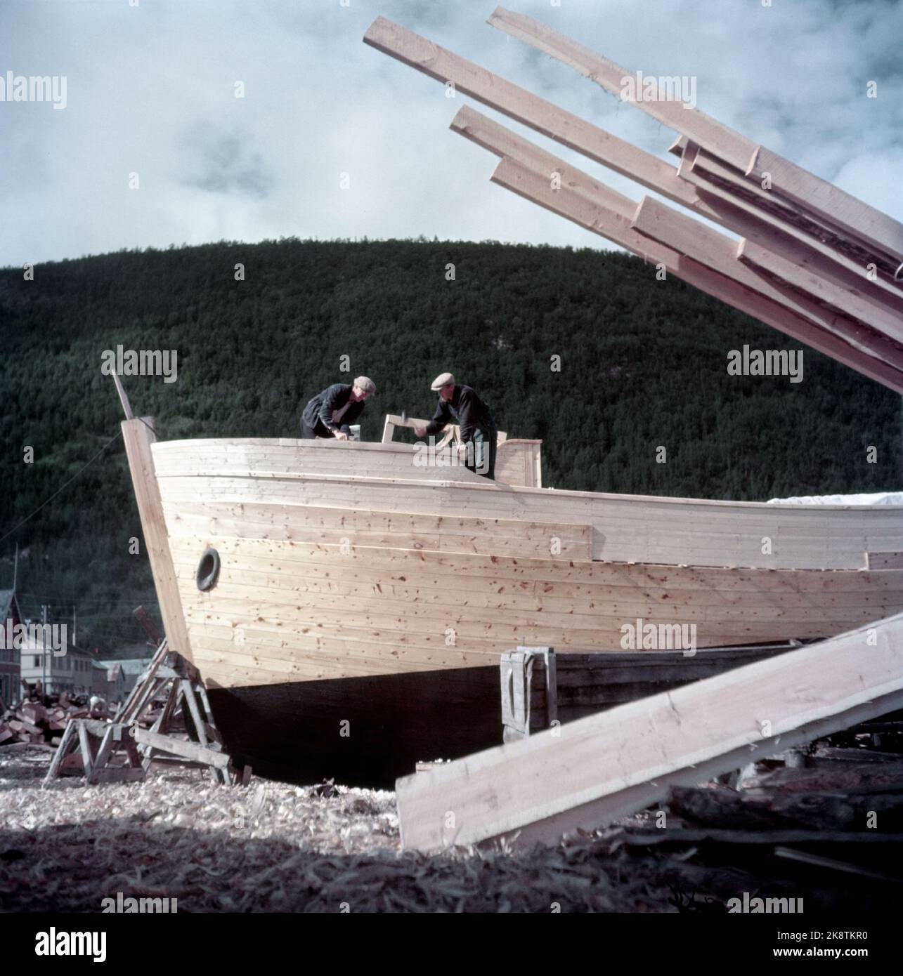 Rognan innerst i Saltdalsfjorden 19531010. Rognan er kjent over hele Nord-Norge som stedet hvor fiskeskøyter bygges Og repareres. Småskipsbyggingen har urgamle tradisjoner, for hundrevis AV år siden sto Folk Og bygde båter i små skur nede i Fjæra. De fleste bøndene har en båt for seg selv på låven i vedskjulet eller i et skur. Båtene bygges i mørke Høst--Og vinterdager når arbeidet med gardsbruket ikke stjeler så mange timer AV døgnet. Langs hele stranda i Rognan er skøyter under bygging eller til reparasjon. Foto: Sverre A. Børretzen / Aktuell / NTB Stockfoto