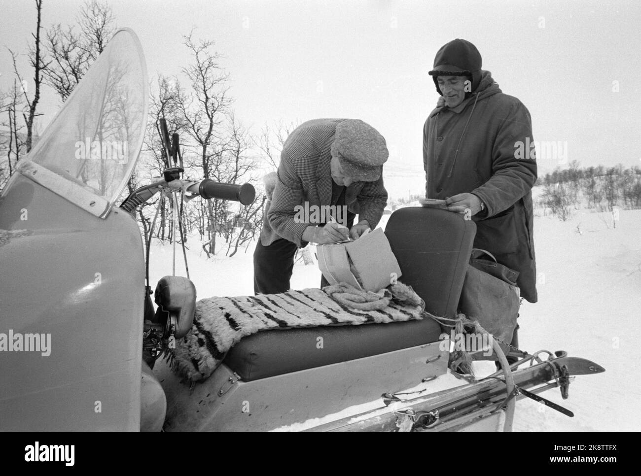 Møsvatn, Telemark 4. Februar 2005. Postbud Erling Skinnarland nutzt Schneemobil bei der Arbeit. Er bezahlte das Schneemobil selbst, NOK 11.000. Hier werden Postdienste auf dem Rollersitz durchgeführt. Der Kunde ist Halvor Åmyri, der das Paket unterzeichnet. Foto: Aage Storløkken / Aktuell / NTB Stockfoto