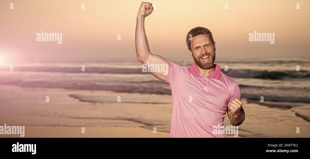 Mann Gesicht Porträt, Banner mit Kopierraum. Erfolgreicher Kerl am Sonnenaufgangsstrand. Bärtiger Mann im Hemd. Feiern Sie Erfolg. Sommerurlaub. Stockfoto