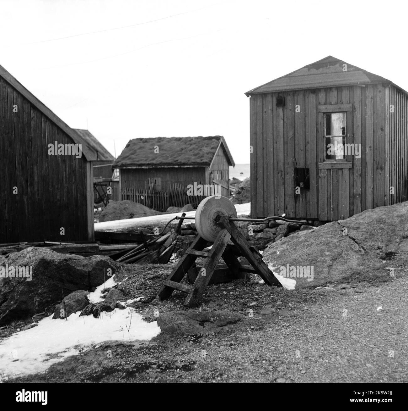 Lofoten, Winter 1951. Mehrere Fischerdörfer in Lofoten werden geräumt, weil sie ohne Strom, Straßen-, Kais- und Telefonanschluss nicht betrieben werden können. An einigen Orten haben die Gemeinden beantragt, Geld vom Staat zu bewegen, um die Häuser und die gesamte Bevölkerung zu bewegen. Hier aus Refsvik, wo die meisten Häuser verlegt wurden, aber die Zehe bleibt und wird kaum bewegt. Im Vordergrund ein alter Schleifstein. Foto: Sverre A. Børretzen / Aktuell / NTB Stockfoto