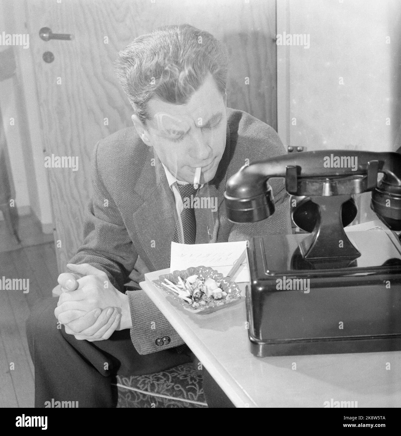 Oslo 1956. Ein Mann nimmt eine Zigarette, während er auf das Telefon wartet. Altmodisches Telefon. Foto: Sverre A. Børretzen / Aktuell / NTB Stockfoto