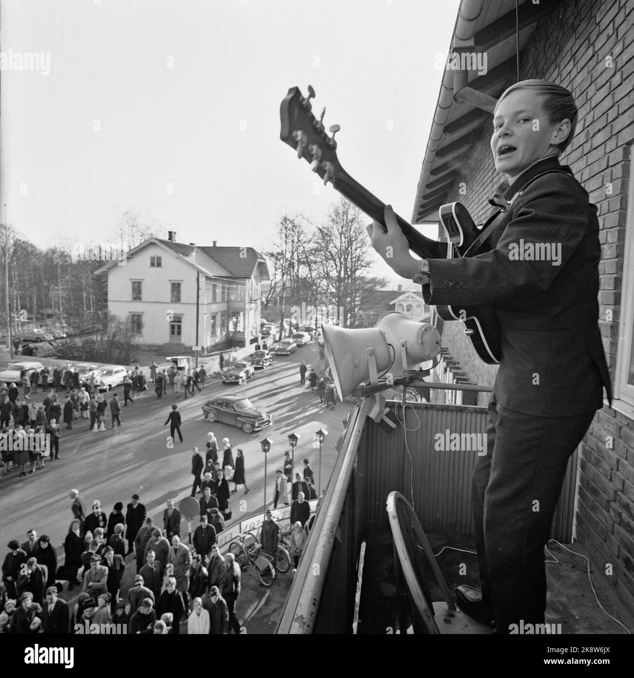 Magnor Oktober 1965: Bargelfolg für norwegische Margarine Allerheiligen kamen fast zehntausend verpackte Autos aus Schweden nach Magnor, um subventionierte norwegische Lebensmittel wie Zucker, Margarine und Weizenmehl zu handeln. Die überwiegende Mehrheit war im Kaufhaus für den 'Margarine King' per Løken. Hier setzt sich der 12-jährige Johnny Skoog mit Gitarre und Gesang auf, auf einem Stockstuhl auf dem Zwiebelbalkon stehend. Foto: Aage Storløkken / Aktuell / NTB Stockfoto
