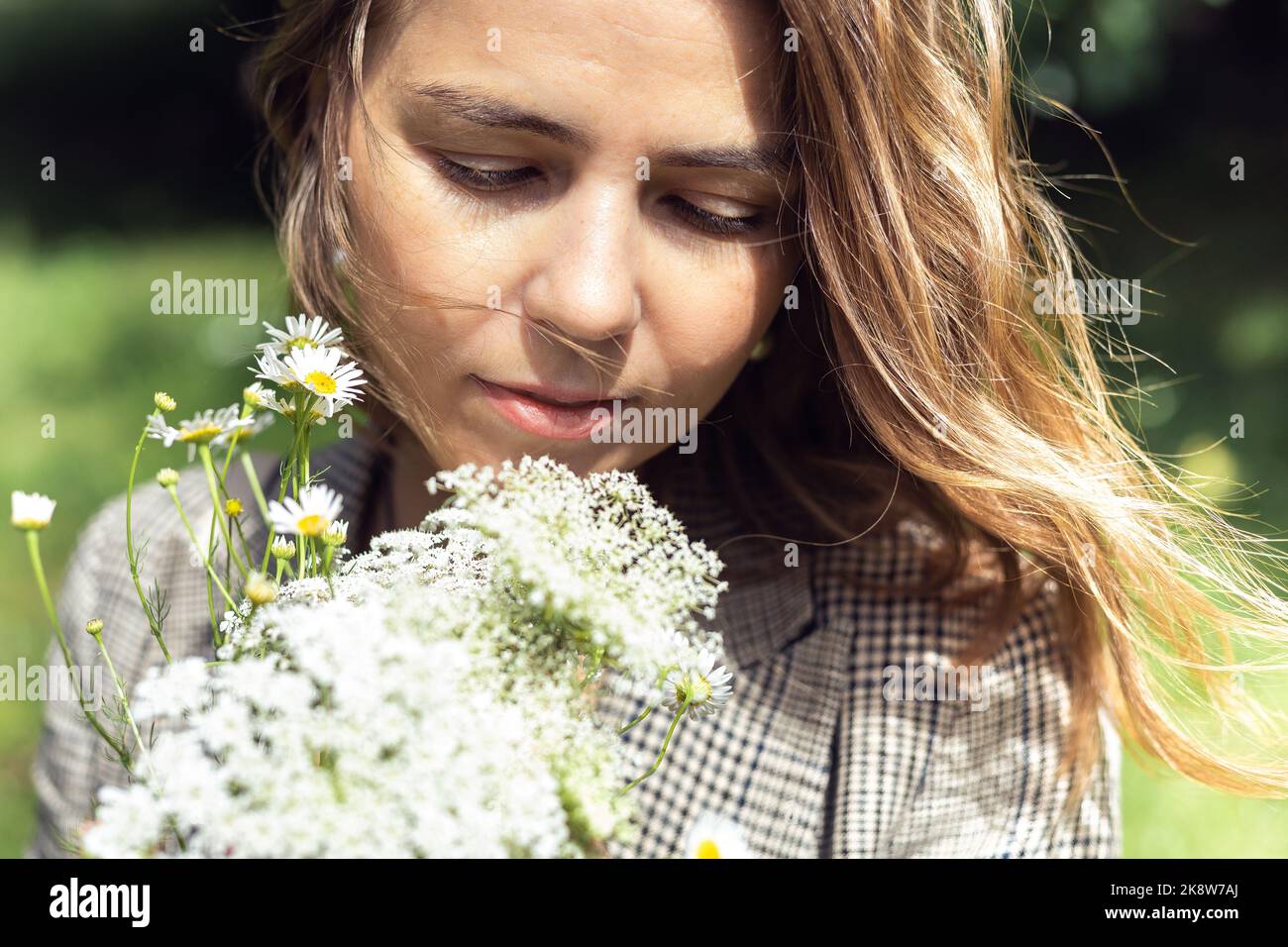 Nahaufnahme blonde, ruhige blonde Frau, die einen Strauß von Feldblumen hält und ihn riecht. Aromatherapie oder Allergie. Naturpark Stockfoto