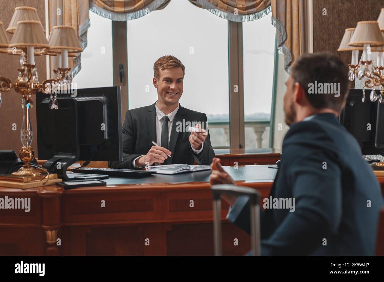 Ein männlicher Geschäftsmann checkt im Luxushotel ein und erhält die Schlüsselkarte von der Rezeption Stockfoto