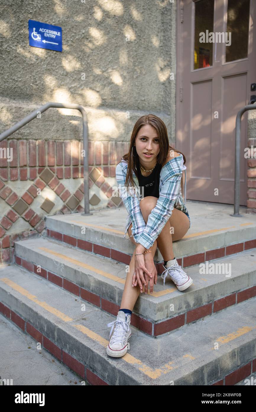 Skateboarderin Girl sitzt vor einem Gebäude in SJSU Stockfoto