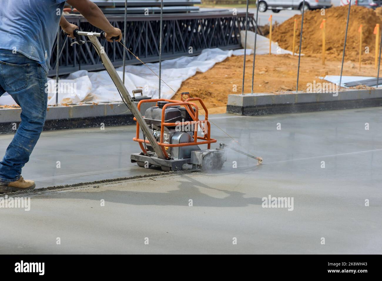 Arbeiter, die Schneidmaschine verwenden, schneiden Beton für die Dehnungsisolierung der Verbindung von Fundamentbeton nach dem Eingießen auf der Baustelle Stockfoto