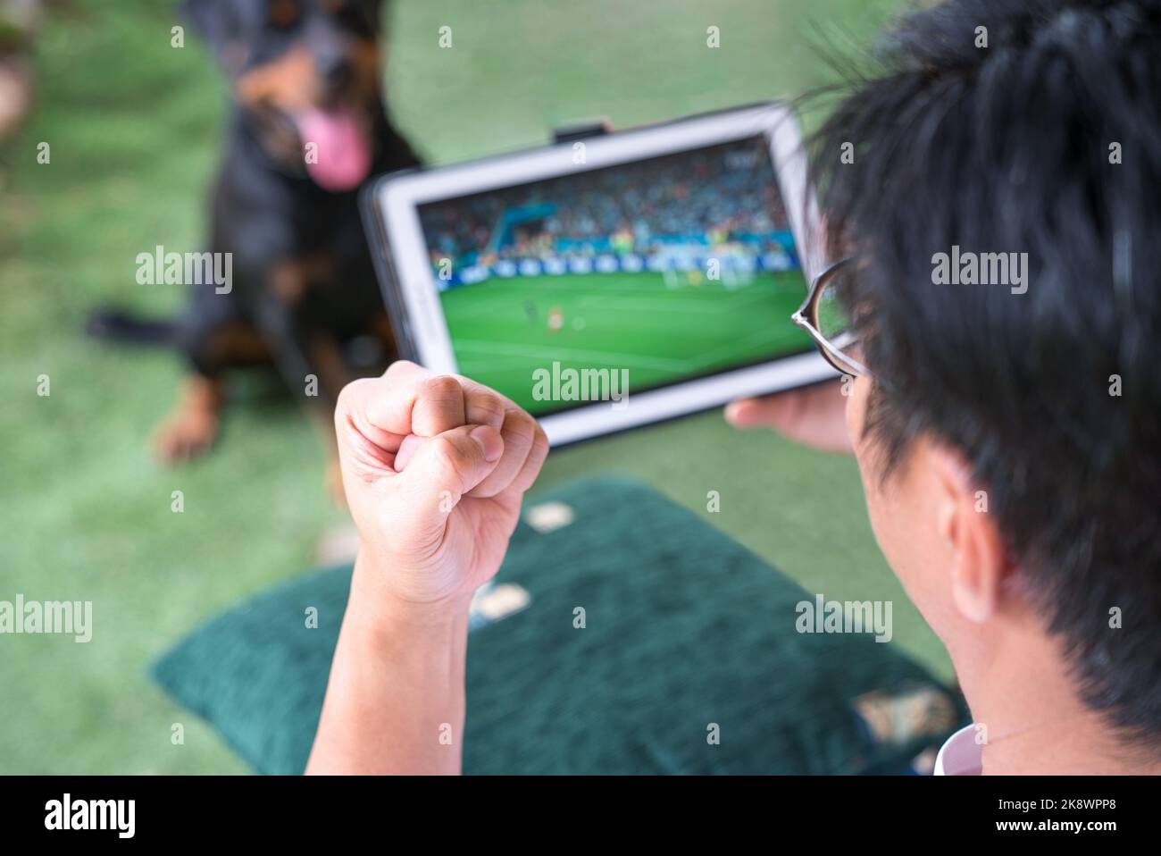 Mann mit der Faust nach oben, während er Fußballsportspiele auf einem digitalen Tablet ansieht. Live-Stream oder Sport Online-Konzept. Stockfoto