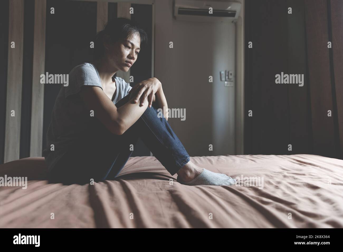 Asiatische Frau, die im Hausbereich sitzt, fühlt sich traurig, müde und besorgt über Depressionen, psychische Probleme und herzzerreißende Konzepte. Stockfoto