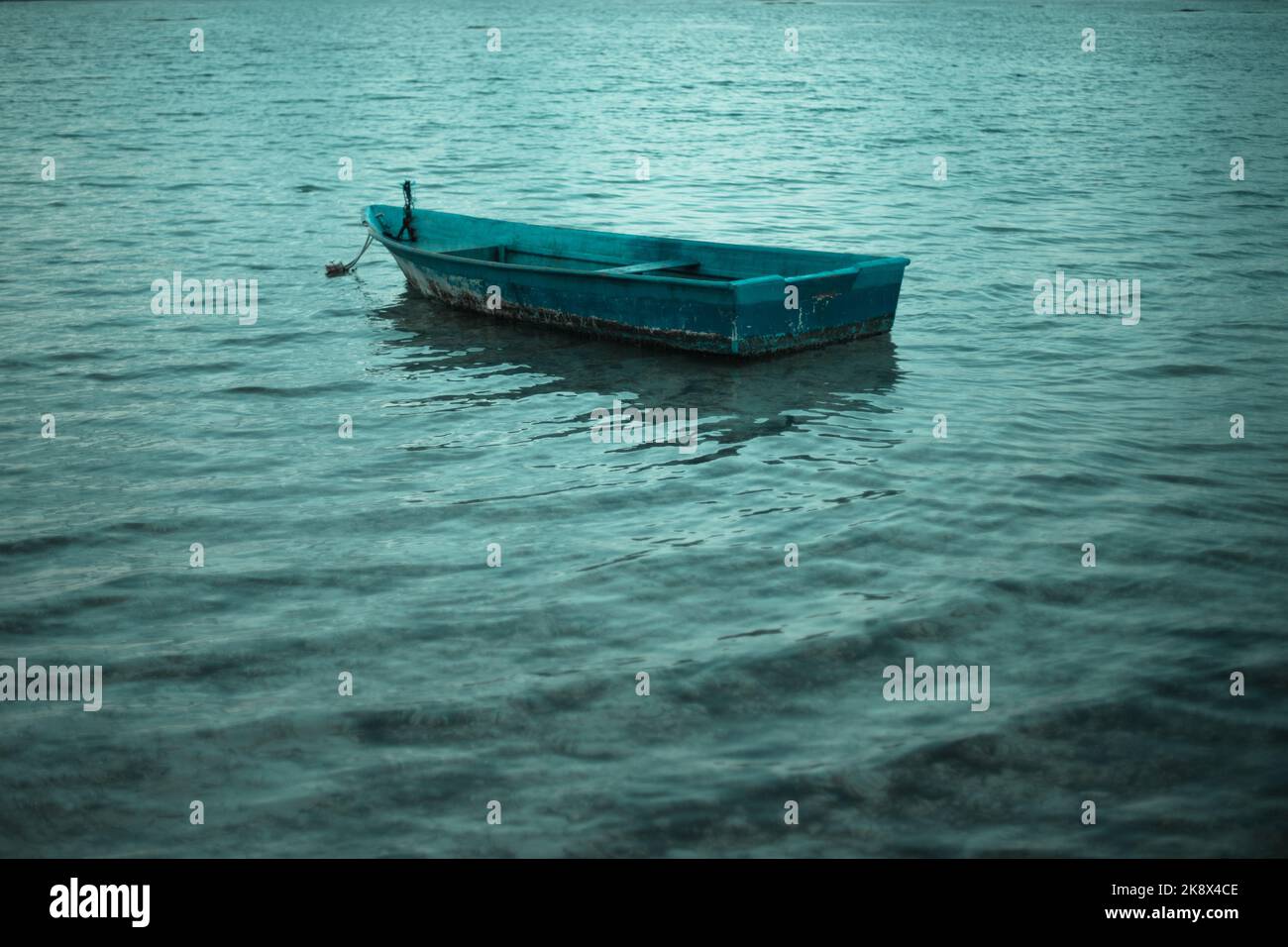 Altes, alleinstehendes Boot, das im ruhigen Wasser schwimmt Stockfoto