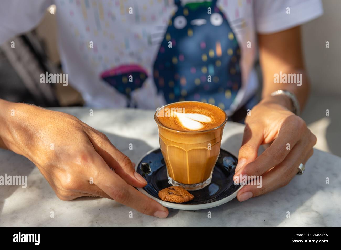 Frau mit einem Glas heißen Latte. Bali, Indonesien. Kein Gesicht. Stockfoto