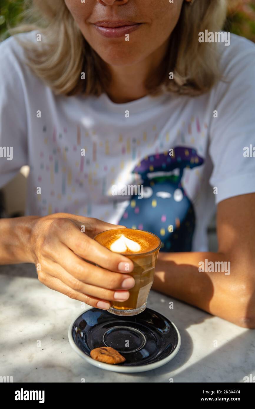 Frau mit einem Glas heißen Latte. Bali, Indonesien. Kein Gesicht. Stockfoto