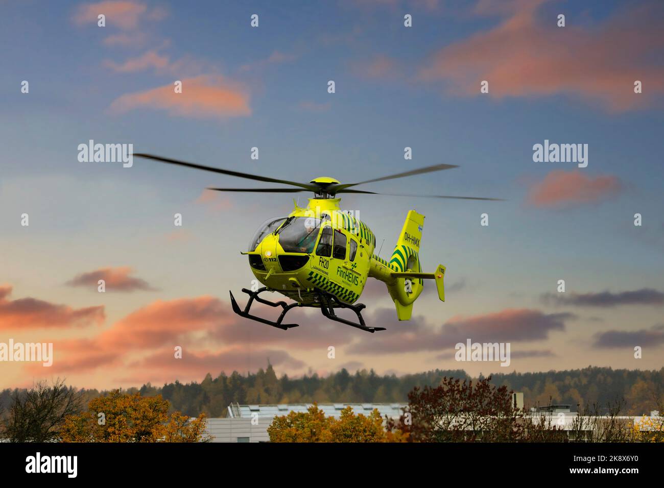 FinnHEMS, Finnish Helicopter Emergency Medical Services, medizinischer Hubschrauber hebt in der Stadt gegen den Sonnenuntergangshimmel ab. Stockfoto