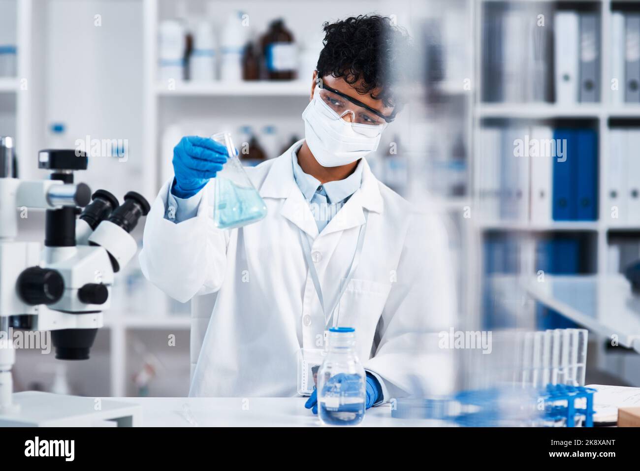 Ich könnte heute einige neue Durchbrüche machen: Ein junger Wissenschaftler, der einen Becher in einem Labor hält. Stockfoto