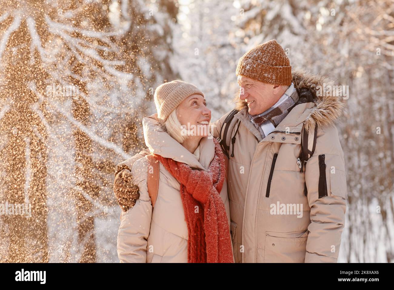 Waist-up-Porträt eines liebevollen älteren Paares umarmt in Winterwald mit Schnee fallen Stockfoto Waist-up-Porträt eines liebevollen älteren Paares umarmt in Winterwald mit Schnee fallen Stockfoto