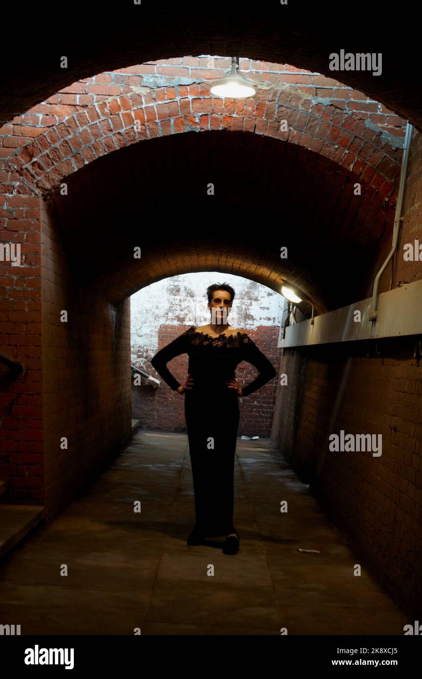 Ganzkörperportrait einer kaukasischen Frau in stehender Pose in der Horsted Keynes Station Underpass, West Sussex, Großbritannien. Modell: Der Universelle Appell. Stockfoto