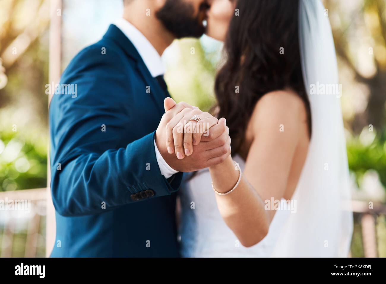 Heute entschieden sie sich für Engagement. Ein unbekanntes frisch verheiratetes Paar küsst sich, während es an ihrem Hochzeitstag die Hände hält. Stockfoto