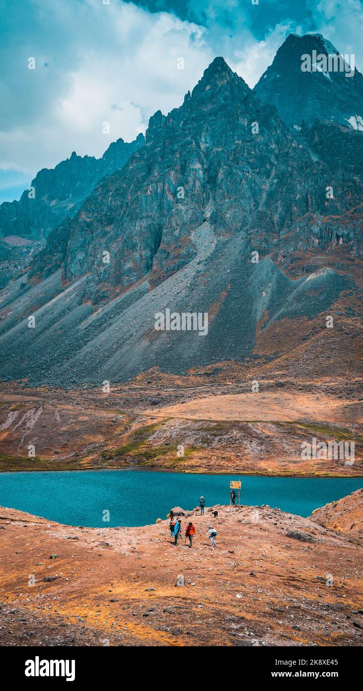 Ein vertikaler Blick auf den Berg Nevado Auzangate in Peru über See und Touristen Stockfoto