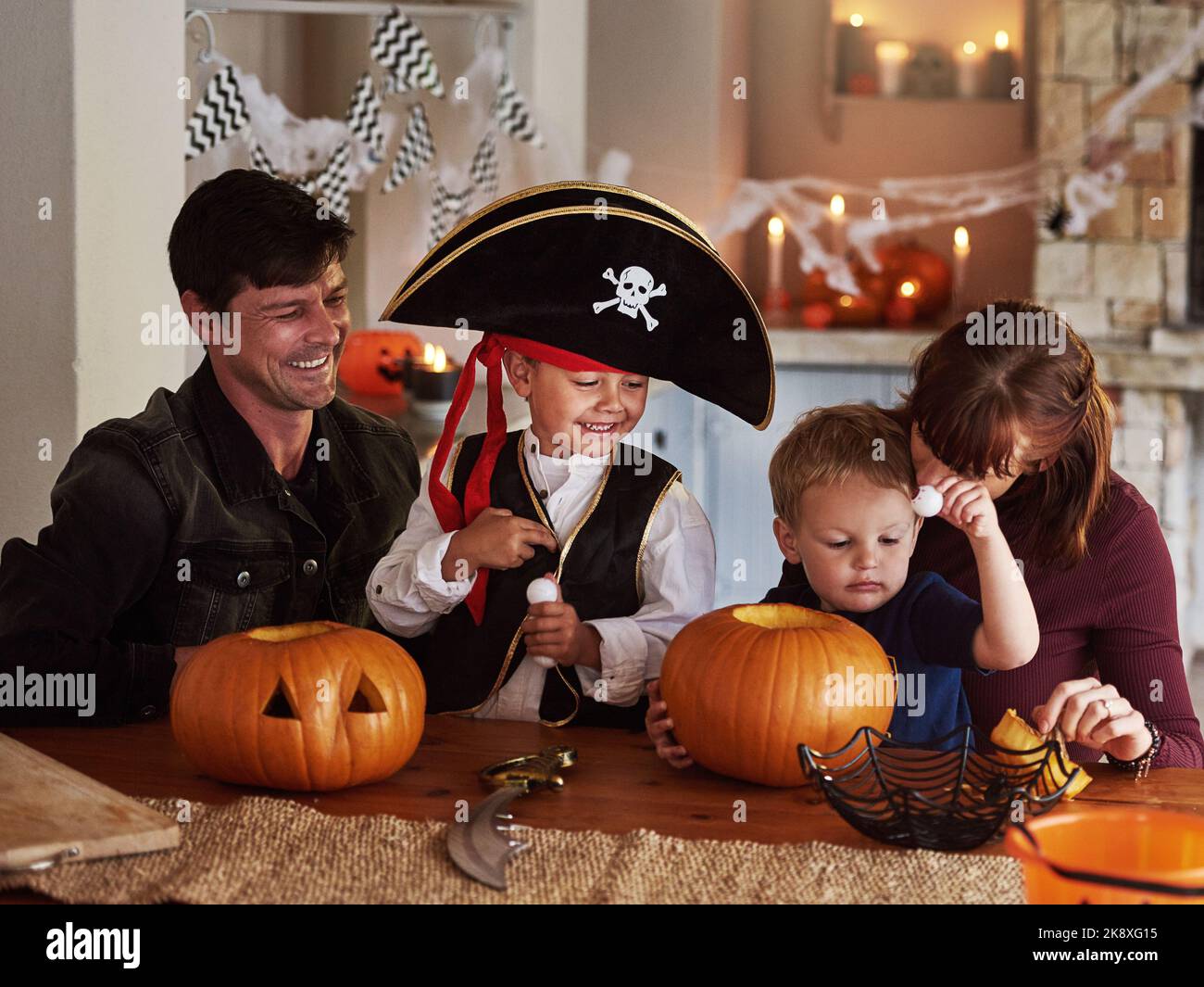 Halloween-Spaß mit der Familie. Eine entzückende junge Familie schnitzt Kürbisse aus und feiert halloween zusammen zu Hause. Stockfoto