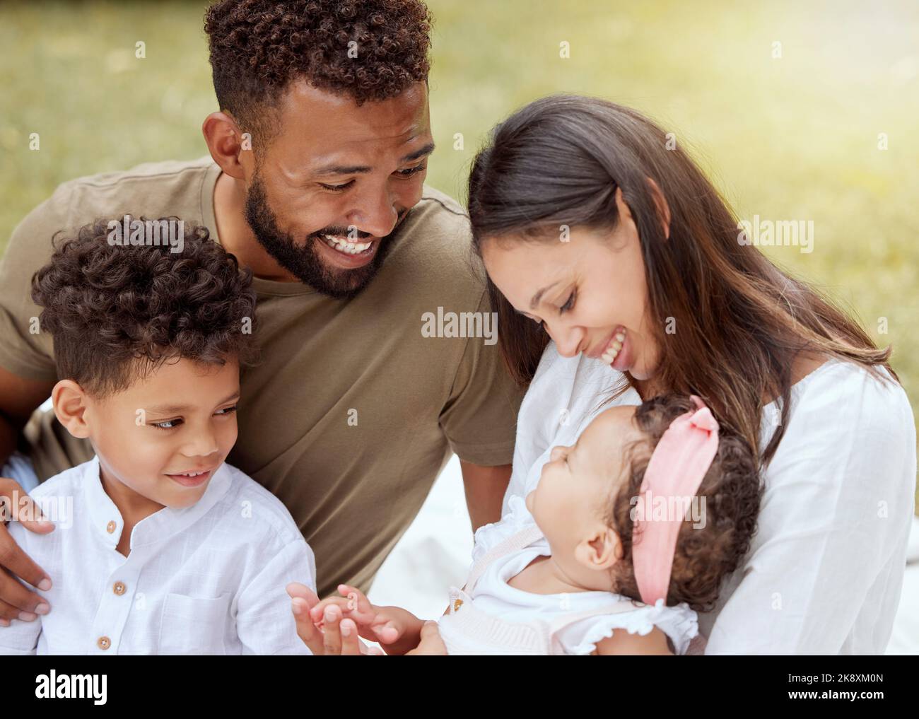 Glückliche Familie, Liebe und Baby entspannen sich in einem Garten, lachen und binden, während sie auf Gras in einem Hinterhof spielen Stockfoto