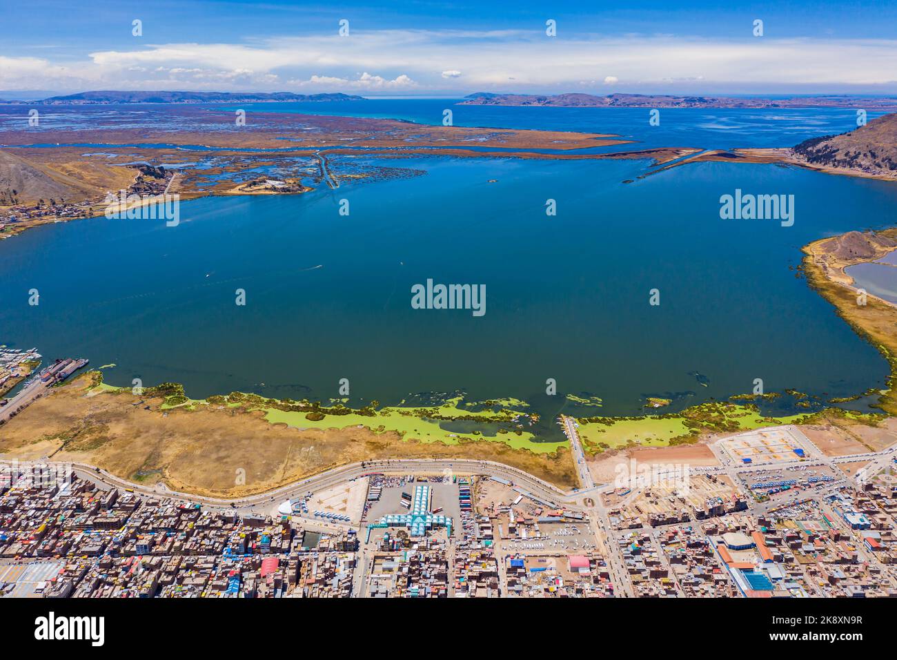 Luftaufnahme des Titicacasees in Peru mit der Stadt Puno und seinem Hafen im Vordergrund. Stockfoto