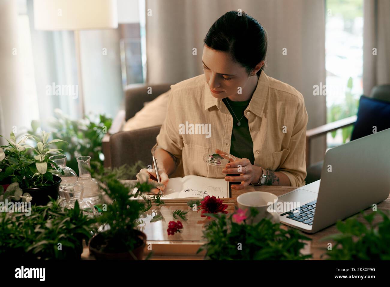 Ich notieren jedes kleine Detail. Eine attraktive junge Floristin, die auf ihrem Notizblock schreibt, während sie eine Checkliste der Blumen in ihrem Geschäft macht. Stockfoto