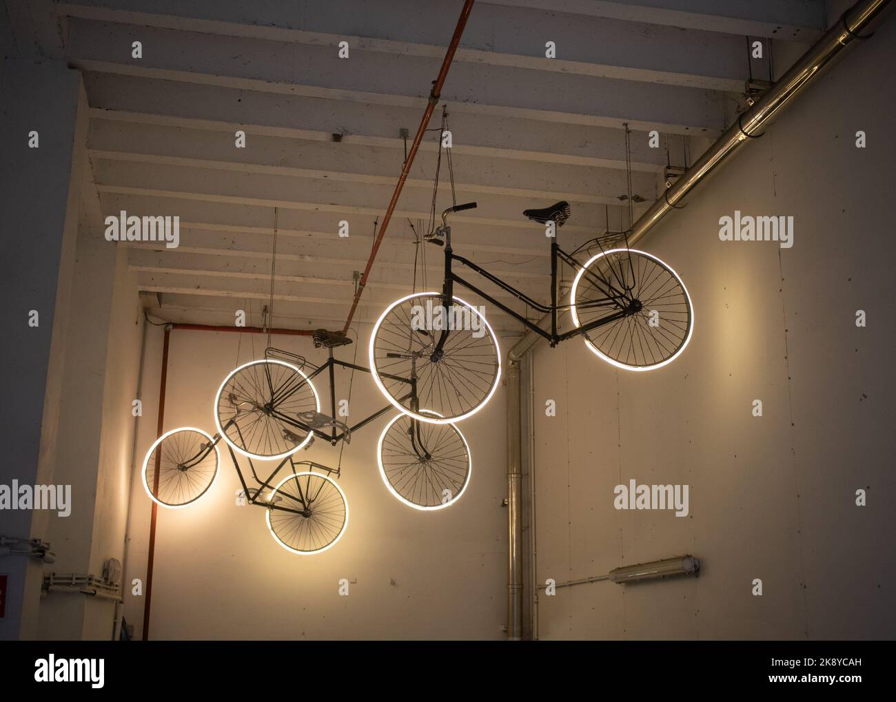 Moderne Kunstinstallation mit beleuchteten Rädern, die von einem Garagendach hängen Stockfoto