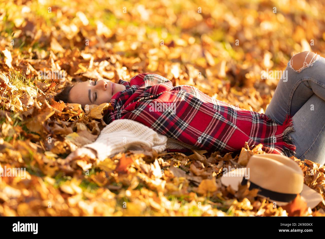 Sorglos schöne Brünette im Park liegend entspannen während sonnigen Herbst Sonnenuntergang. Stockfoto