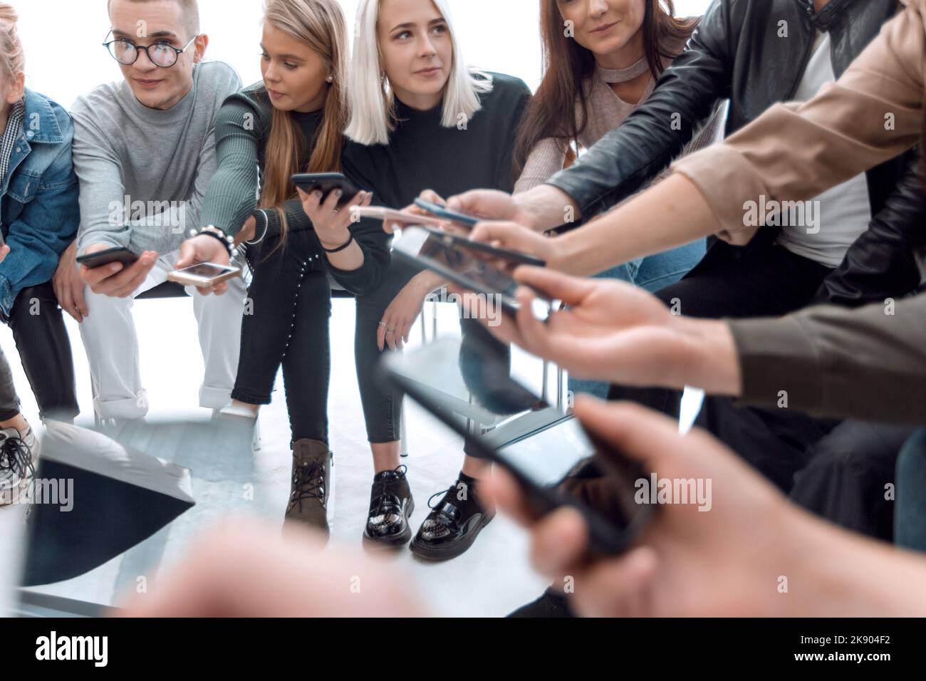 Gruppen junger Menschen, die Nachrichten auf ihrem Smartphone lesen Stockfoto