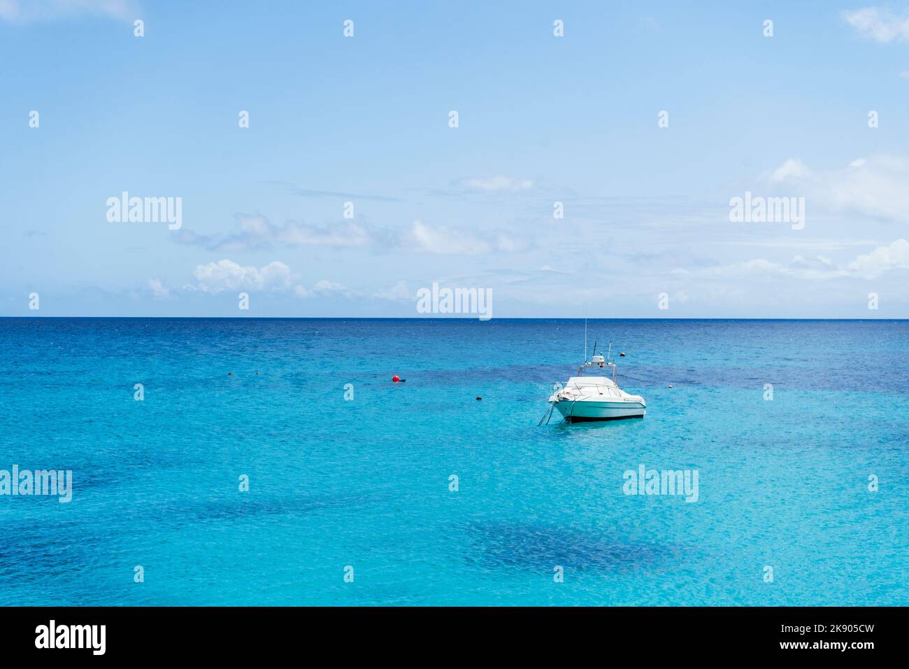 Kleine Yacht auf türkisfarbenem Meer unter blauem Himmel in Punta Mujeres, Lanzarote, Kanarische Inseln, Spanien Stockfoto