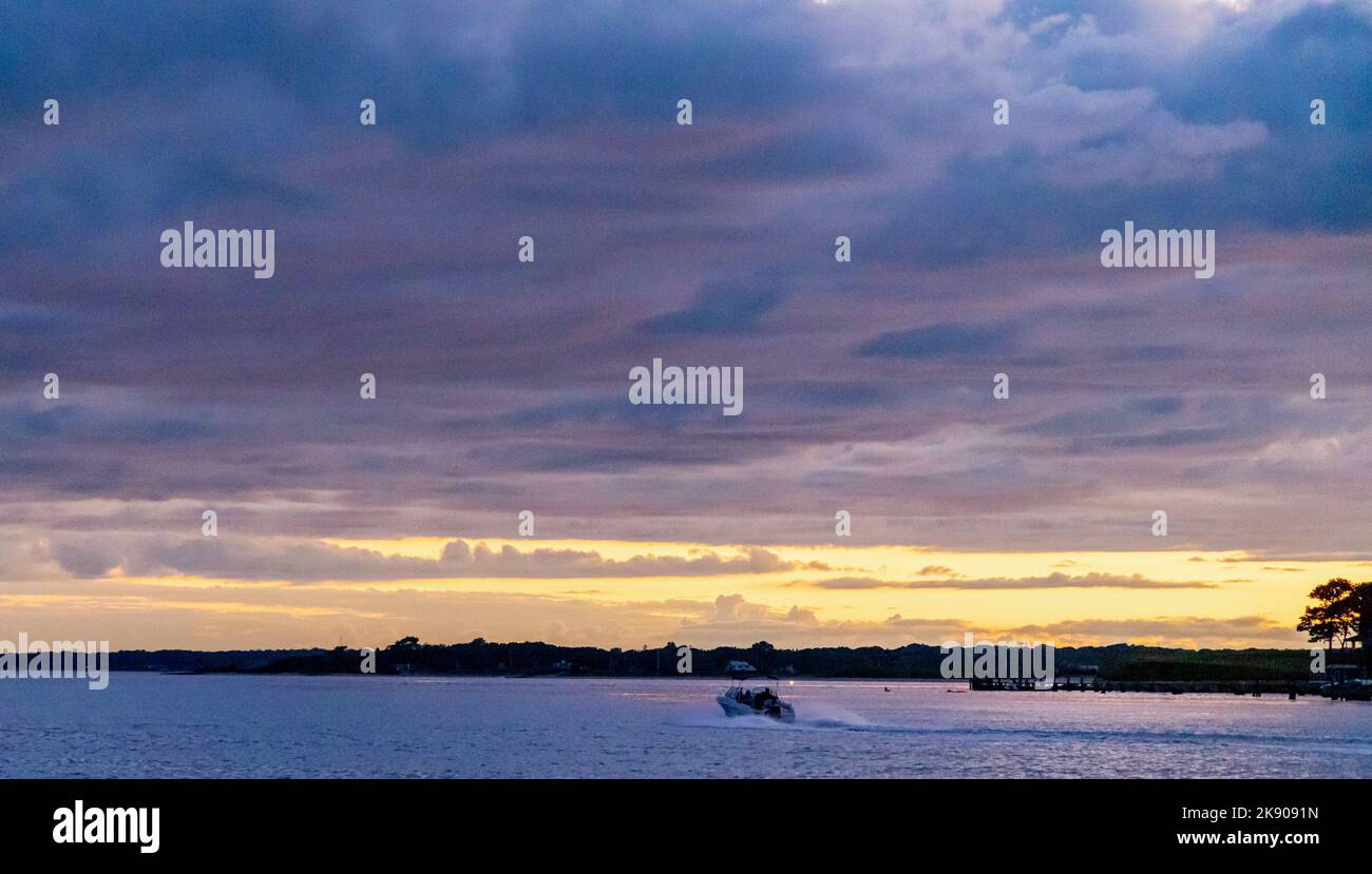 Ein kleines Motorboot unterwegs mit einem brillanten Sonnenuntergang Stockfoto