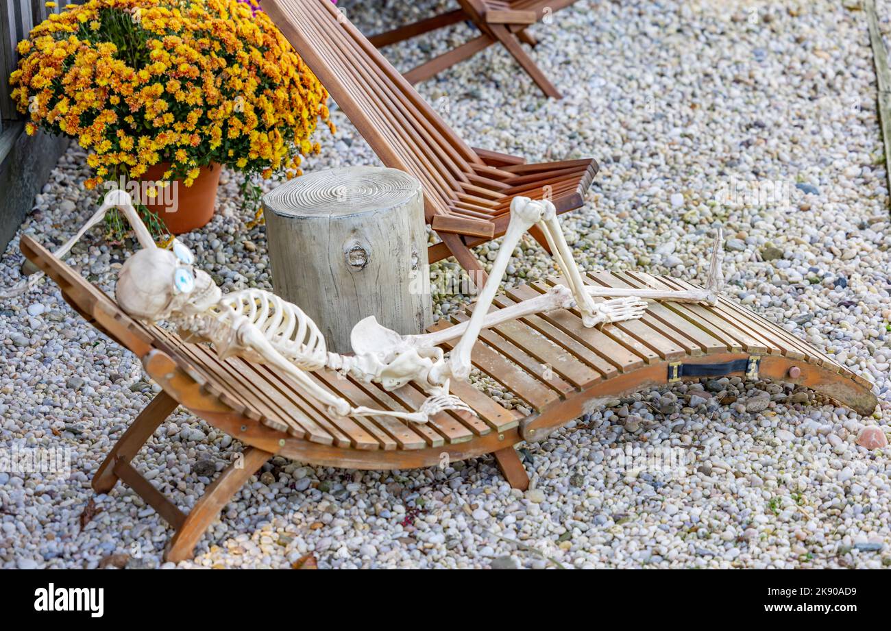 Menschliches Skelett, das sich auf einem Loungesessel im Freien auflehnend Stockfoto