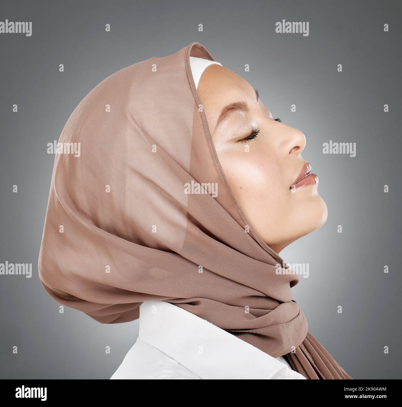 Frau, muslim und Schönheit im Hijab-Schal, der islamische Religion vor grauem Studiohintergrund umarmt. Schöner Kopf des weiblichen Modells im islam mit Ruhe Stockfoto