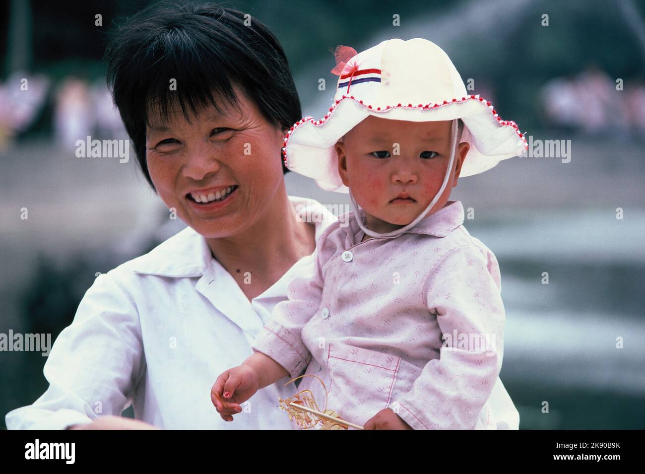 China. Xian. Nahaufnahme des Porträts einer chinesischen Frau, die ein Kind hält. Stockfoto