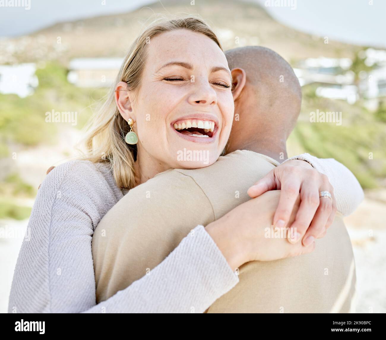Glücklich, Umarmung und Paar am Strand zusammen Lächeln in der Natur Gefühl Liebe und Glück im Freien. Lachend, lächelnd und romantische Erfahrung für ein Stockfoto