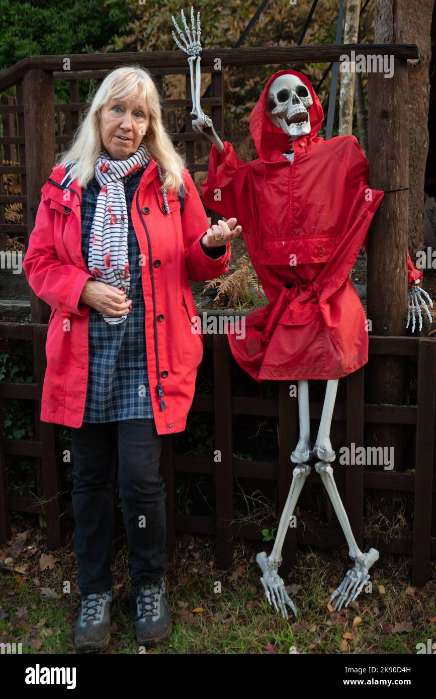 Frau in einem roten Mantel mit Skelett in einem roten Mantel, Halloween im Blue Pool Nature Reserve, Wareham, Purbeck, Dorset, Großbritannien Stockfoto