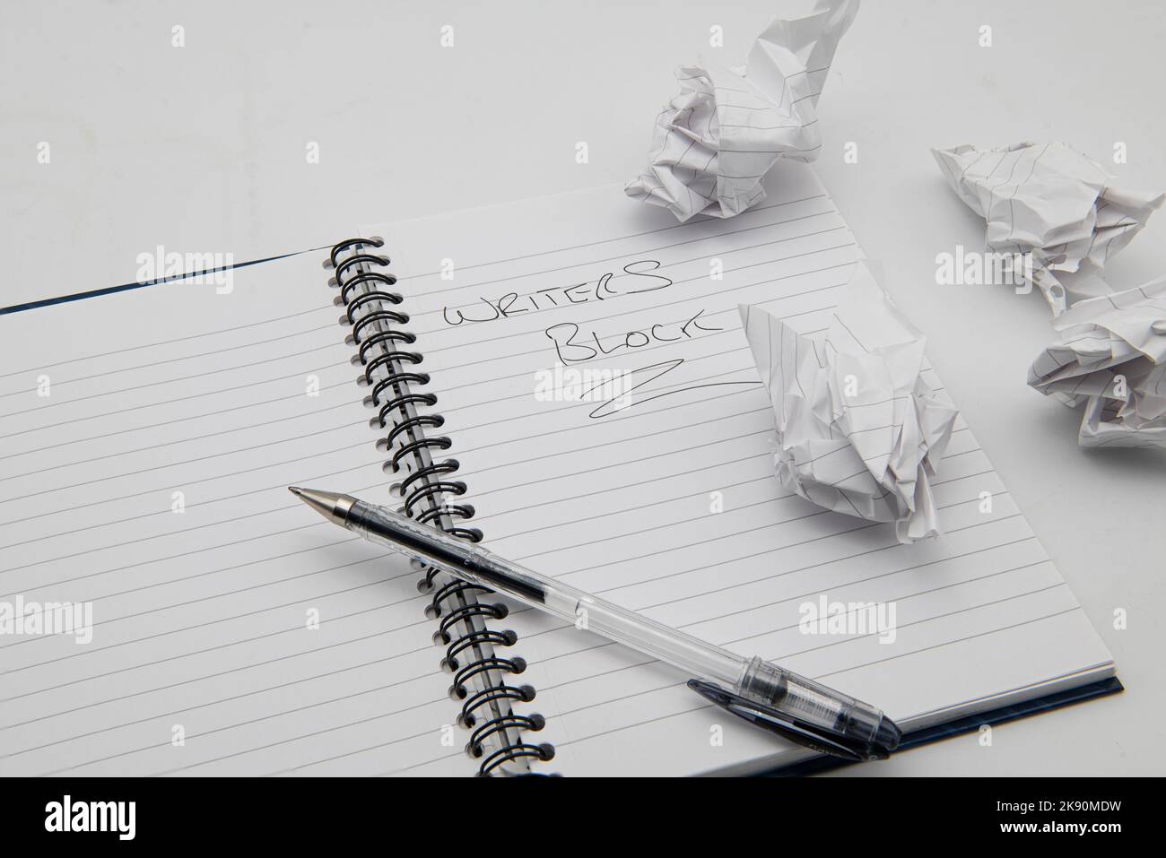 Öffnen Sie das Buch mit einem Stift und einer Notiz, die besagt, dass Schriftsteller mit zerknittertem Papier auf einer Seite blockieren. Stockfoto