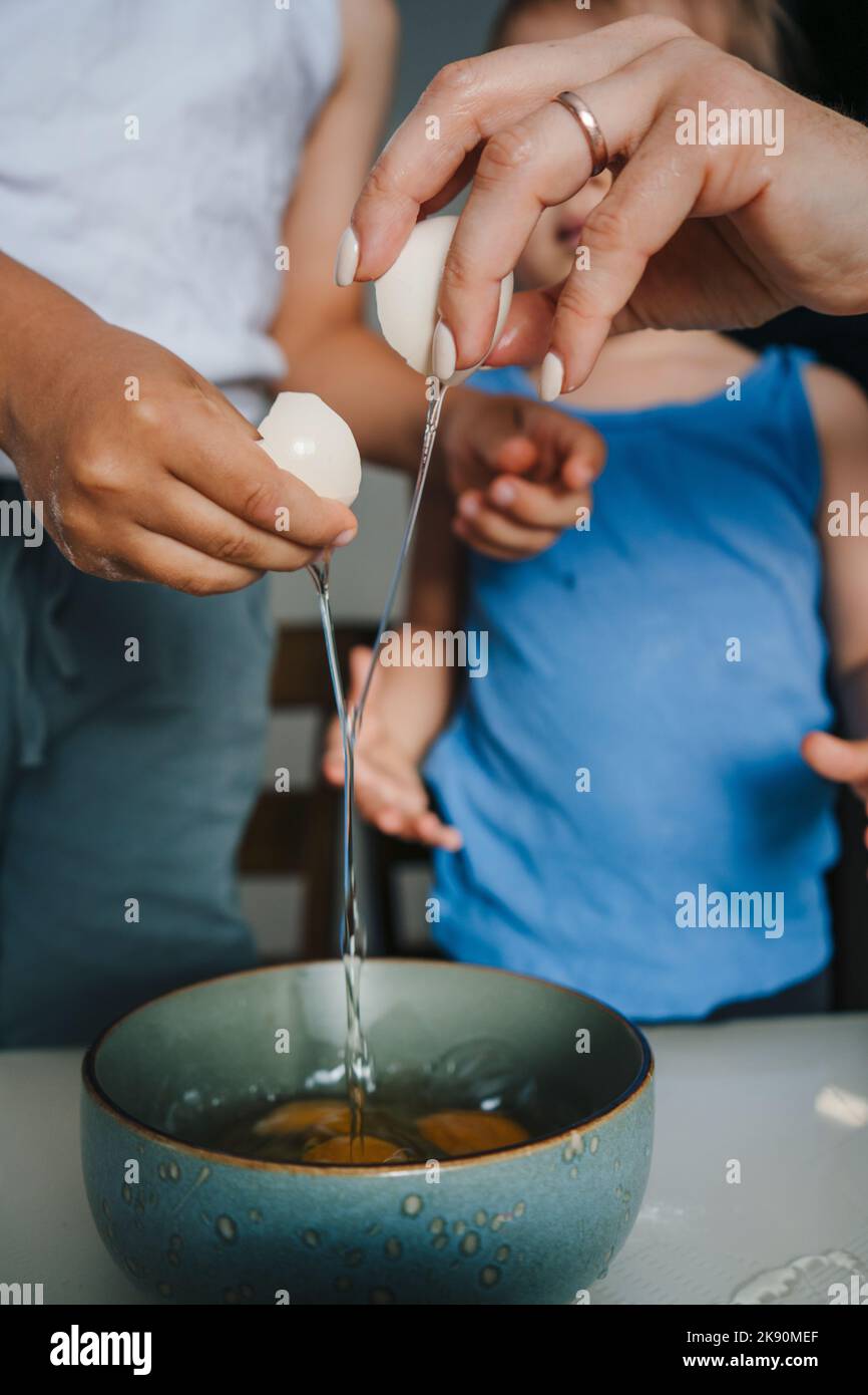Hände von Mutter und Sohn brechen Eier für die Zubereitung von Teig in der Küche. Glückliche Familie, Kindheit. Kinderbetreuung. Lustige Familie. Stockfoto