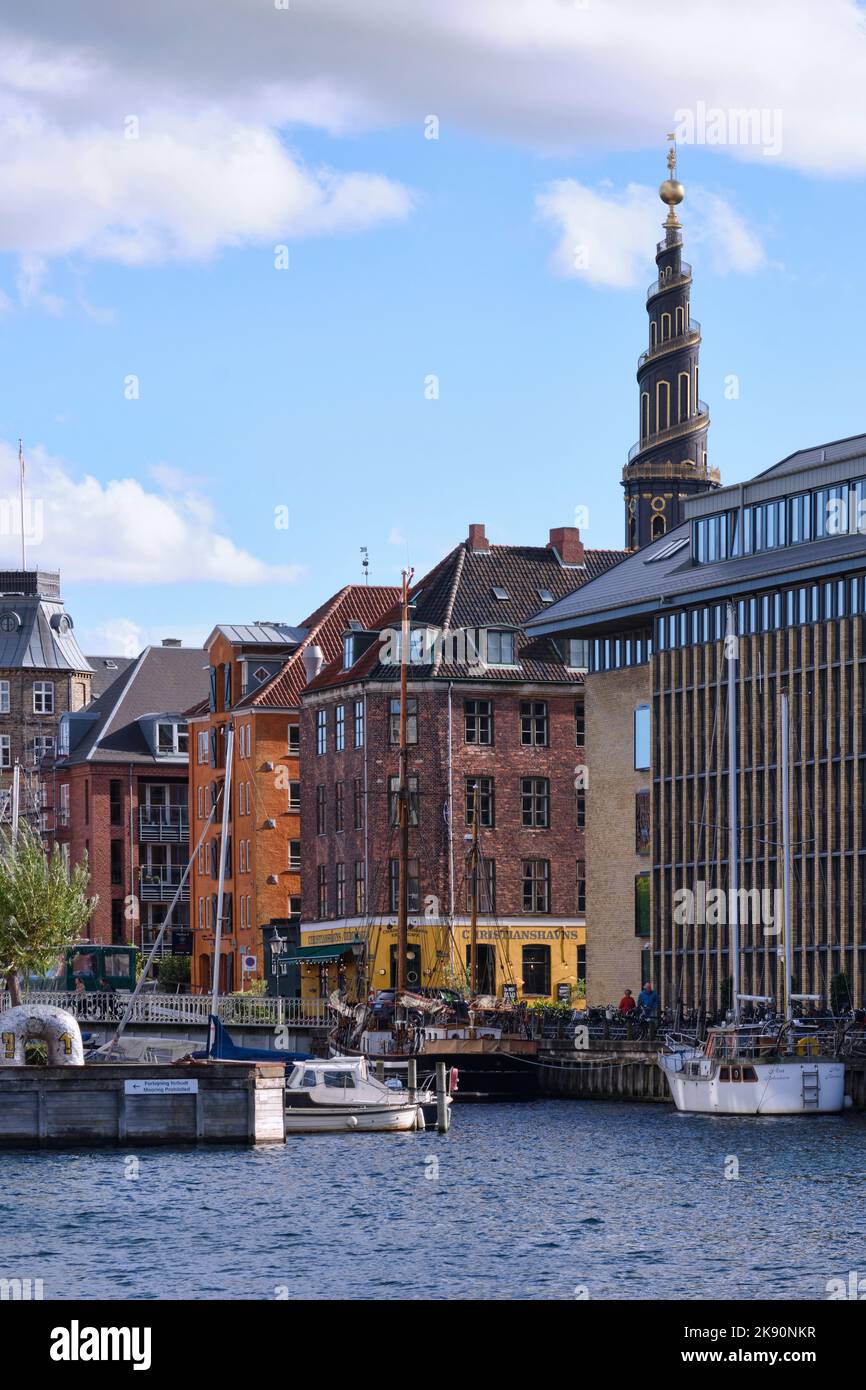 Kopenhagen, Dänemark - 2022. September: Blick über den Kanal in der Stadt gesäumt von historischen Gebäuden im Viertel Christianshavn und der Spitze der Kirche Stockfoto