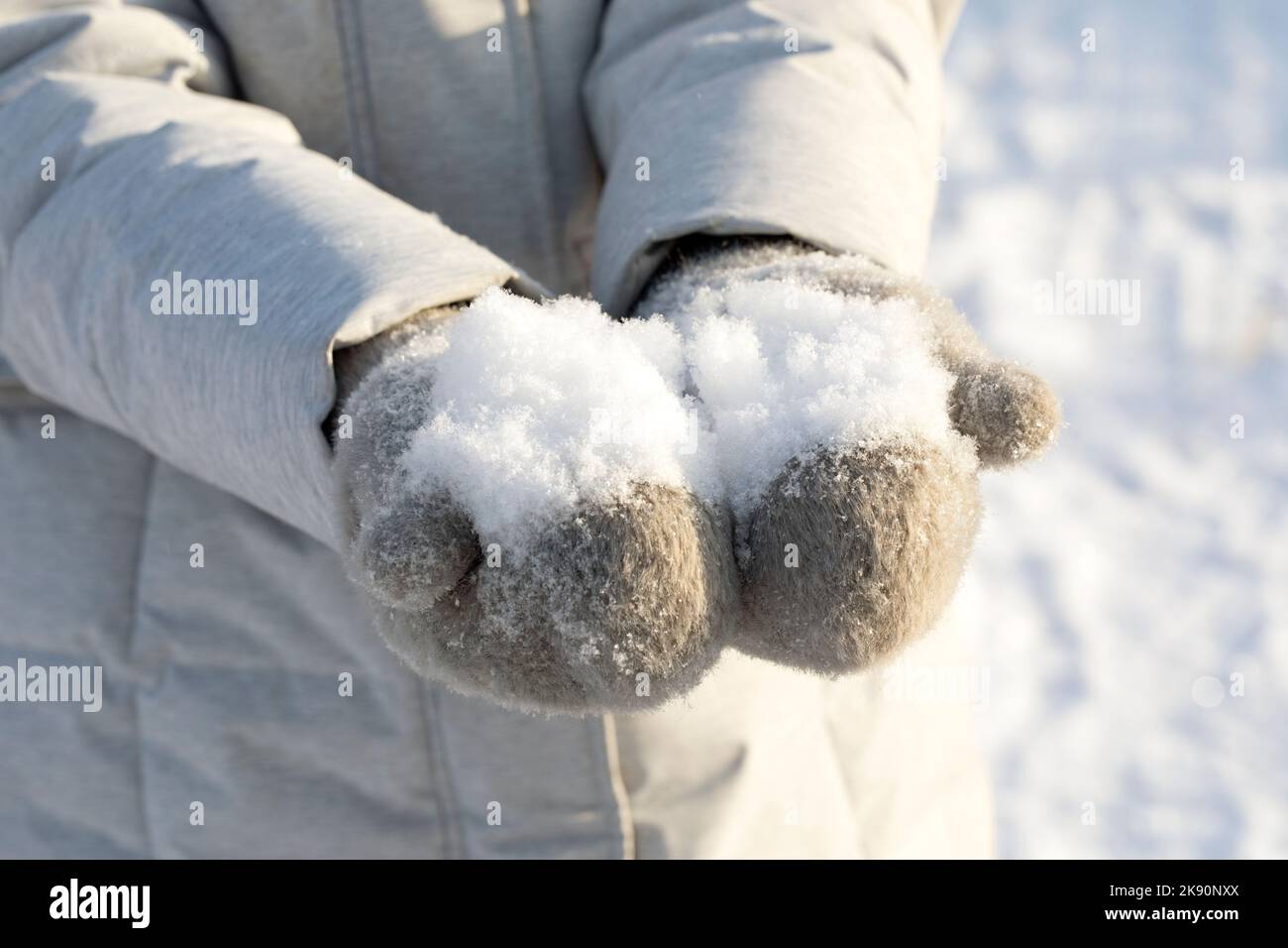 Weißer, weicher, flauschiger Schnee in den Händen von Fäustlingen Stockfoto