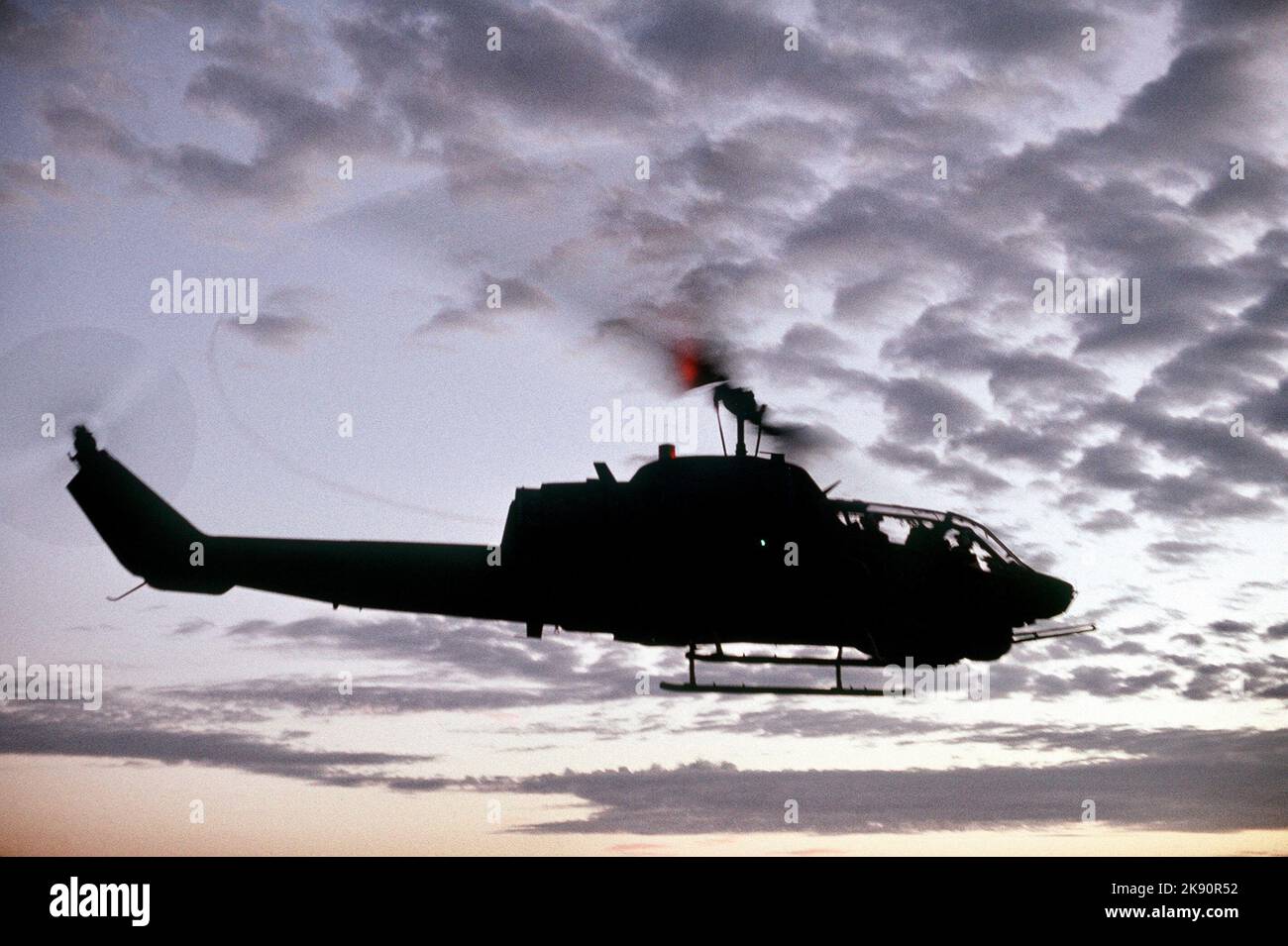 Ein AH-1 Sea Cobra Kanonenschiff wird nach dem Start vom Flugdeck des amphibischen Angriffsschiffes USS Belleau Wood (LHA 3) gegen einen Abendhimmel silhouettiert. Piloten üben Starts und Landungen, um das neue Landescheinsystem des Schiffes, 1989, zu evaluieren Stockfoto