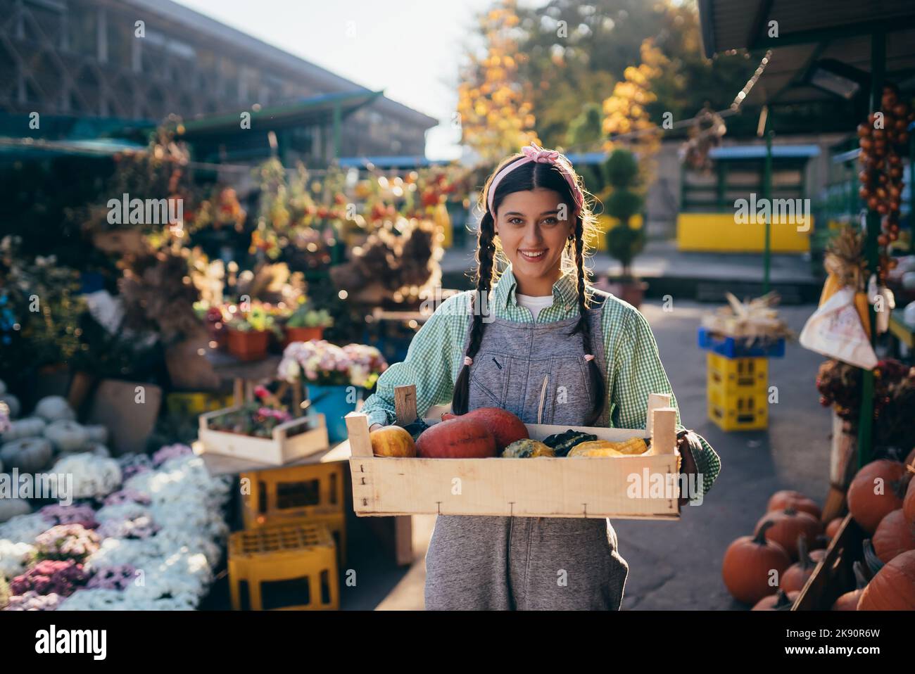 Die Bäuerin hält eine Holzkiste mit Kürbissen in den Händen Stockfoto
